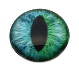 Close-up of a green and blue glass cat or dragon eye on a white background