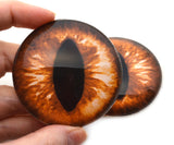 Close-up of a hand holding a large, detailed dragon or cat eye model against a white background