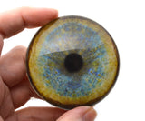 Hand holding a round, leopard glass eye with a multicolored design